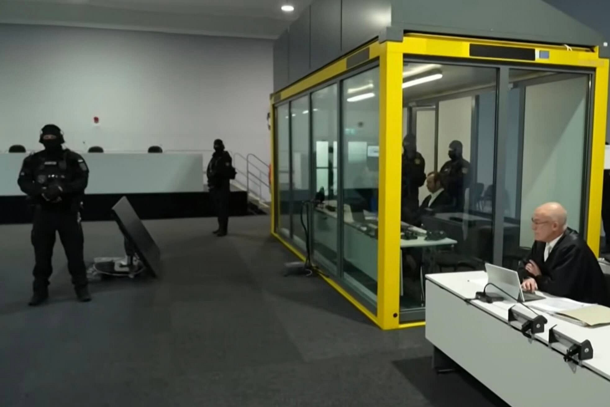 Glaskäfig, Masken – und eine Justiz, die zur Show wird